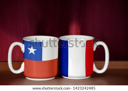 France and Chile flag on two cups with blurry background