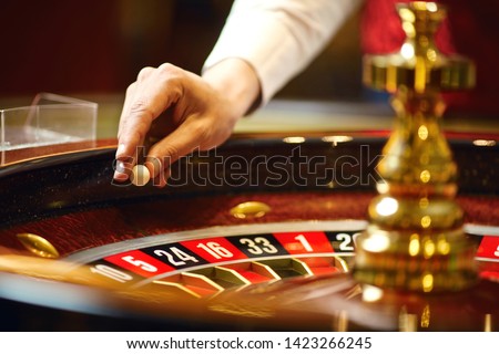 The croupier holds a roulette ball in a casino in his hand. Royalty-Free Stock Photo #1423266245