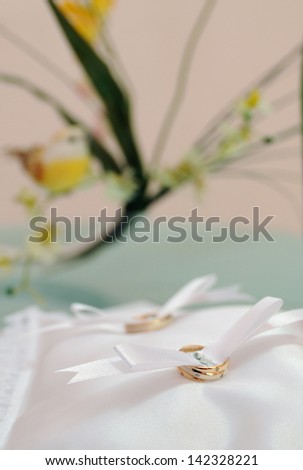 gold wedding rings on a pillow in the registry office