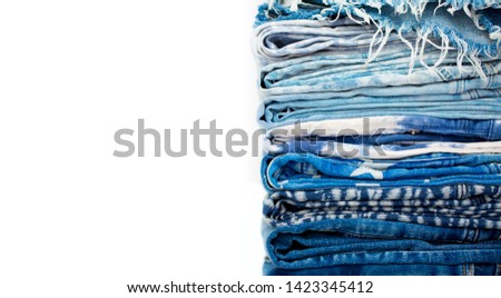 Stack of jeans neatly folded on a white background. Denim closeup of different design. Fashion and style, casual wear.