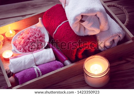 SPA consist from colorful towels, pink sea salt and candles on a wooden tray. Picture in Low-key lighting