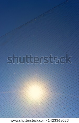 The sun shines through the net against the sky