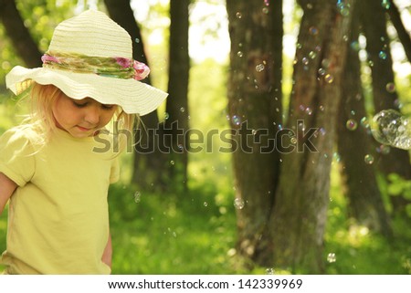 beautiful little girl in a hat on the nature