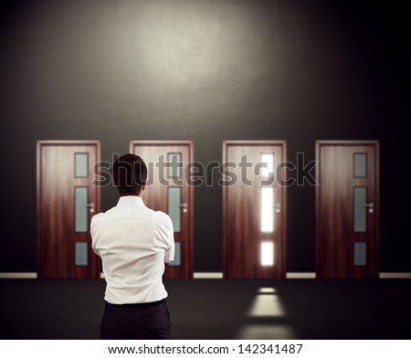 businessman looking at four doors and pondering over decision. focus on man Royalty-Free Stock Photo #142341487