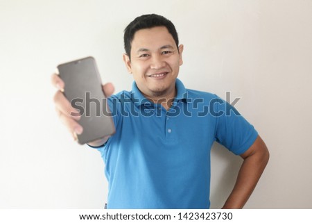 Portrait of young young Asian man presenting smart phone mockup with selective focus