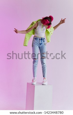 a woman with pink hair stands in a neon spotlight cube