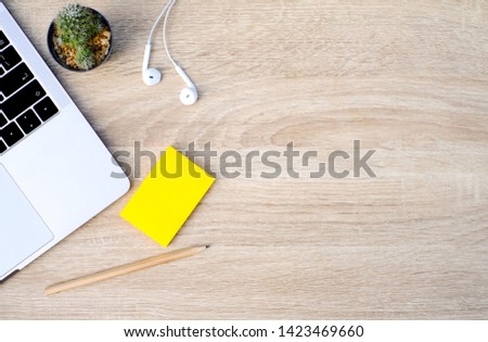 Wood office desk table with laptop and listening music with white headphone, pencil, Yellow stick note and cactus. Top view of brown wooden office desk table with copy space, flat lay, Work space