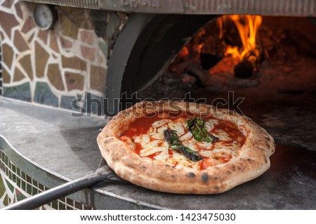 Hot pizza Margherita on the peel just out of the wood-fired oven. Royalty-Free Stock Photo #1423475030