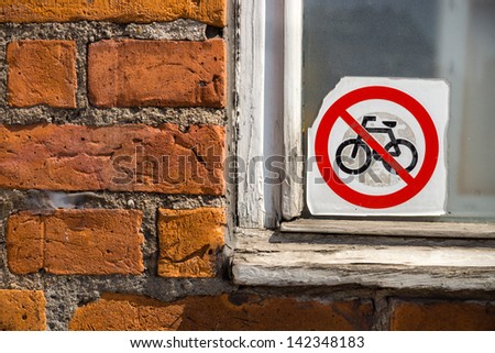 no bikes here: a 'no bikes allowed' sticker, on a window next to a brick wall