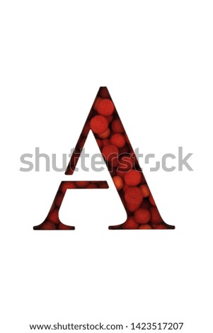 A white PVC sheet with a cut out letter A. Against the backdrop of woolen balls of red color. Close-up