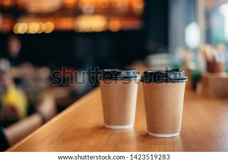 Two paper cups with a lid for tea to go. Coffee take away is on the table. There is space for text in the background. Royalty-Free Stock Photo #1423519283