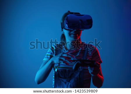 Young cute girl playing vr with gamepad. with creative blue-red light. Emocyanally and fun.concept gaming