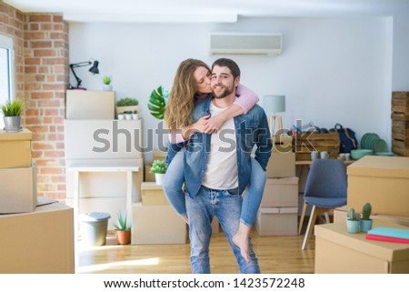Young couple moving to a new house, boyfriend giving a piggy bac