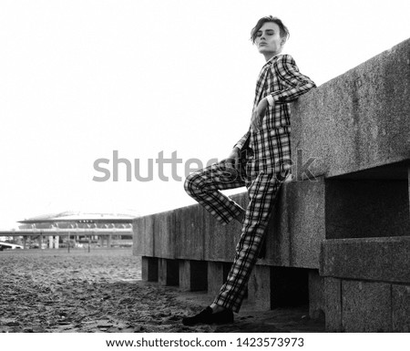 handsome fashion male model dressed in elegant suit posing outdooe. Long haired Metrosexual. Black and white picture.