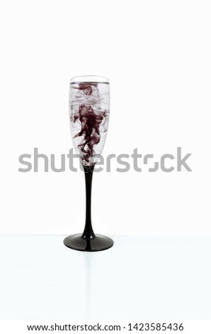 Wine glass on white background with black color paints inside. Fougere for champagne with black smoke and streak.