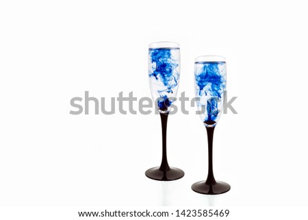 Two wine glasses on white background with blue color paints inside. Fougeres for champagne with smoke and streak.