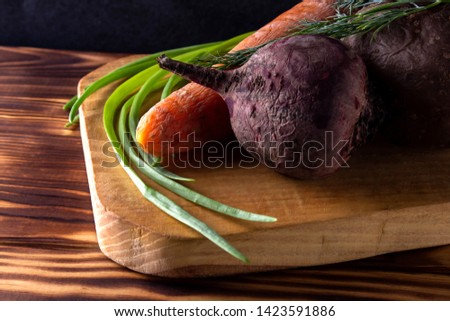 Beet, carrot, potatoe, green onion on wooden cutting board, boiled vegetables, ingredients for salad, wooden table