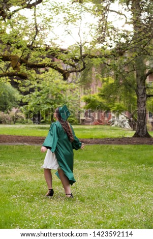 University graduate on her college campus in a cap and gown celebrating graduating from her undergrad bachelor's degree during the Spring.