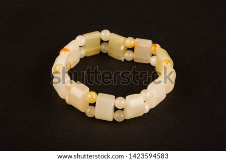 Colorful young girl bracelet isolated on white with green prehnite, yellow cat's eye tiger's eye and dark green canadian jade stones and silver leaf figures at middle