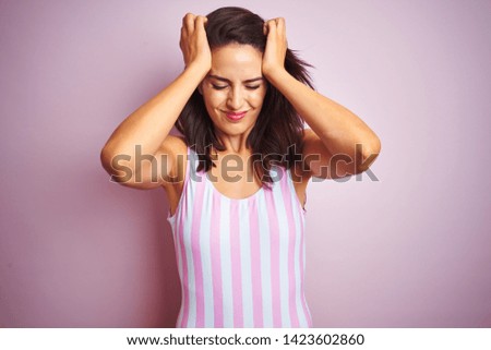 Young beautiful woman wearing striped pink swimsuit swimwear over pink isolated background suffering from headache desperate and stressed because pain and migraine. Hands on head.