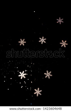 Abstract black background with isolated defocused snowflakes.