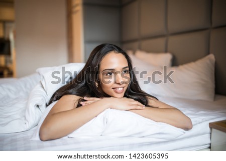 Smiling casual brunette lying in her bed in bright bedroom