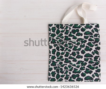 Eco Shopping Bag in trendy leopard pattern print on white wooden background, Top View, Flat Lay