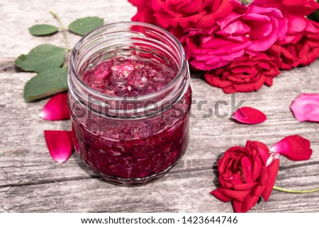 Jar of jam of rose petals on a wooden table with flowers of roses. Flower confiture. Healthy food. Copy space