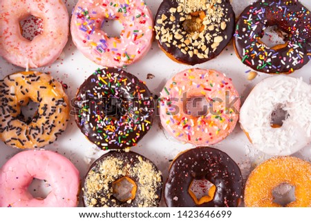 Overhead view of a dozen freshly baked doughnuts Royalty-Free Stock Photo #1423646699
