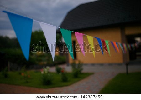 Triangular colorful holiday flags. Multicolored flags in the yard.