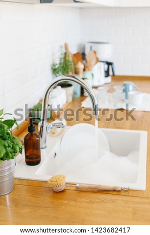 White sink with dishes ready to wash. Modern white kitchen scandinavian style, zero waste eco friendly home