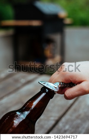 Opening beer bottle in summer evening