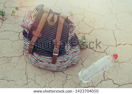 Backpack and a nearby bottle of water on the dried, dried.