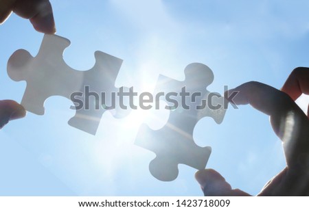 two hands trying to connect couple puzzle piece with sunset background. Jigsaw alone wooden puzzle against sun rays. one part of whole. symbol of association and connection. business strategy