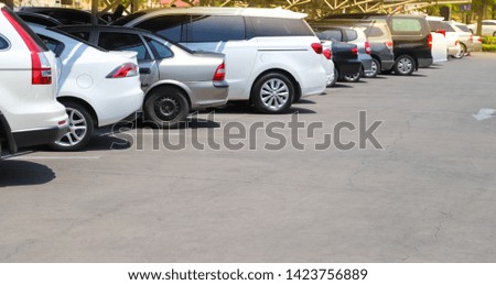 Closeup of rear, back side of white car with  other cars parking in parking lot in bright sunny day. The mean of simply transportation in modern world.