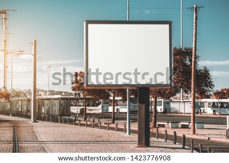 Mockup of a big blank information poster in urban settings near the transport node; an empty horizontal street banner template; an outdoor billboard placeholder mock-up on the pavement near the road