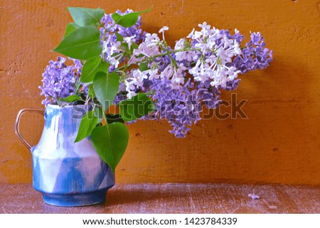 Still life with purple and white garden lilac. Bouquet of flower of lilac in a bowl on an old vintage wooden background