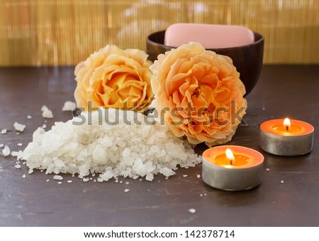 Sea salt in bowl with rose and candles on wooden background.  Selective focus.Spa/wellness products.