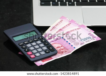 Close up view of brand new indian 2000 rupees banknotes, electronic calculator and  laptop.