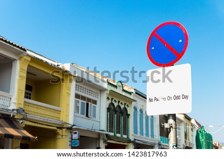 No Parking on Odd Day sign of the circular shape on Sino-Portuguese building and blue sky background. Red and Blue no parking street sign at Phuket city, Thailand.