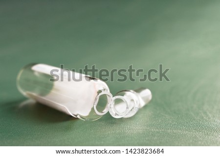 Empty Opened Glass Ampoule with White Label and Its Head, or Conical Tip on Green Background. Copy Space. Royalty-Free Stock Photo #1423823684