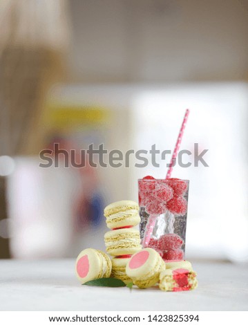 On a light table is a glass of lemonade and macaroon, fruits and berries