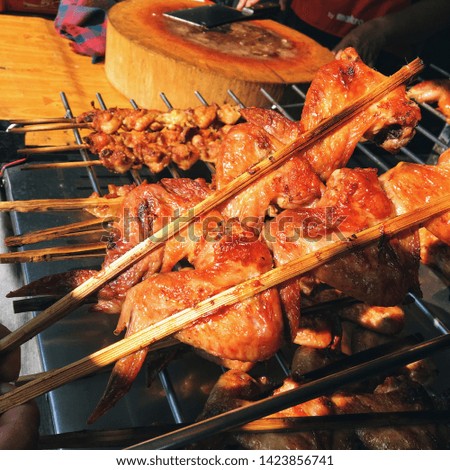 Grilled chicken wings in wooden skewers, Street food in Thailand.