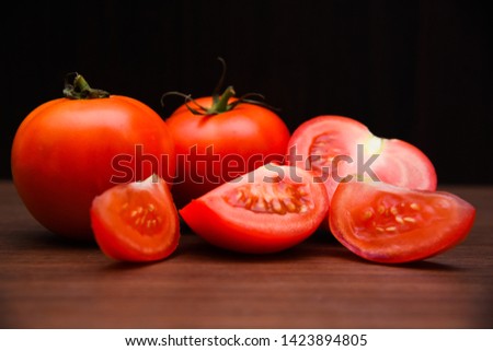 Close-up pictures of bright red tomatoes on the floor, an old wooden table with a black background.