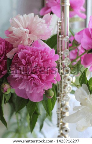 silver flute and a bouquet of pink peonies, color photography