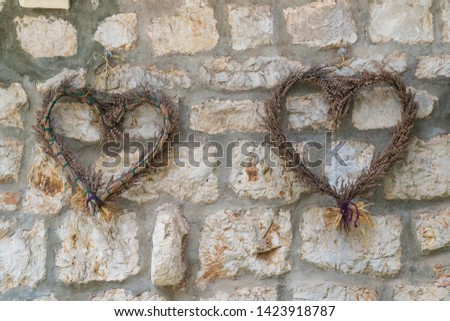 Heart shaped decoration hanging on the stone wall made of wooden sticks and dried flowers