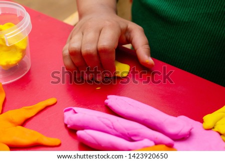 improving fine motor skills educational games concept, modeling colorful clay children's hands close-up red background