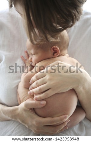 Mom and baby, newborn mom in her arms. Light photo in casual style in real interior, close-up