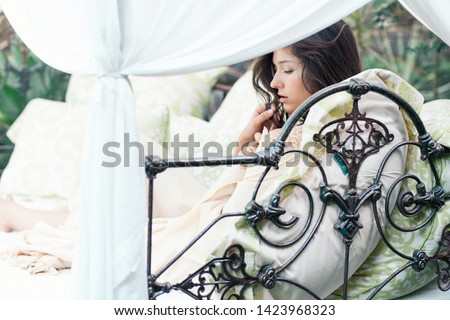 Ideal beutiful woman relaxing in white cozy bed with conopy in tropical jungle garden. Harmony of nature and human beauty. Relax concept.
