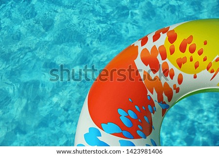 Colorful inflatable ring floating in swimming pool on sunny day, above view. Space for text